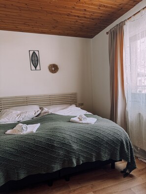 A neatly made bed with a green quilt, white pillows, and rolled towels. - Das Luis (Altenmarkt im Pongau)