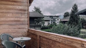 Ein Holzbalkon mit Tisch und Stühlen, mit Blick auf eine Wohngegend.