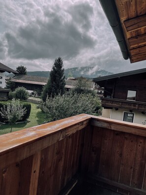 A wooden balcony overlooking a garden with a mountain backdrop. - Das Luis (Altenmarkt im Pongau)