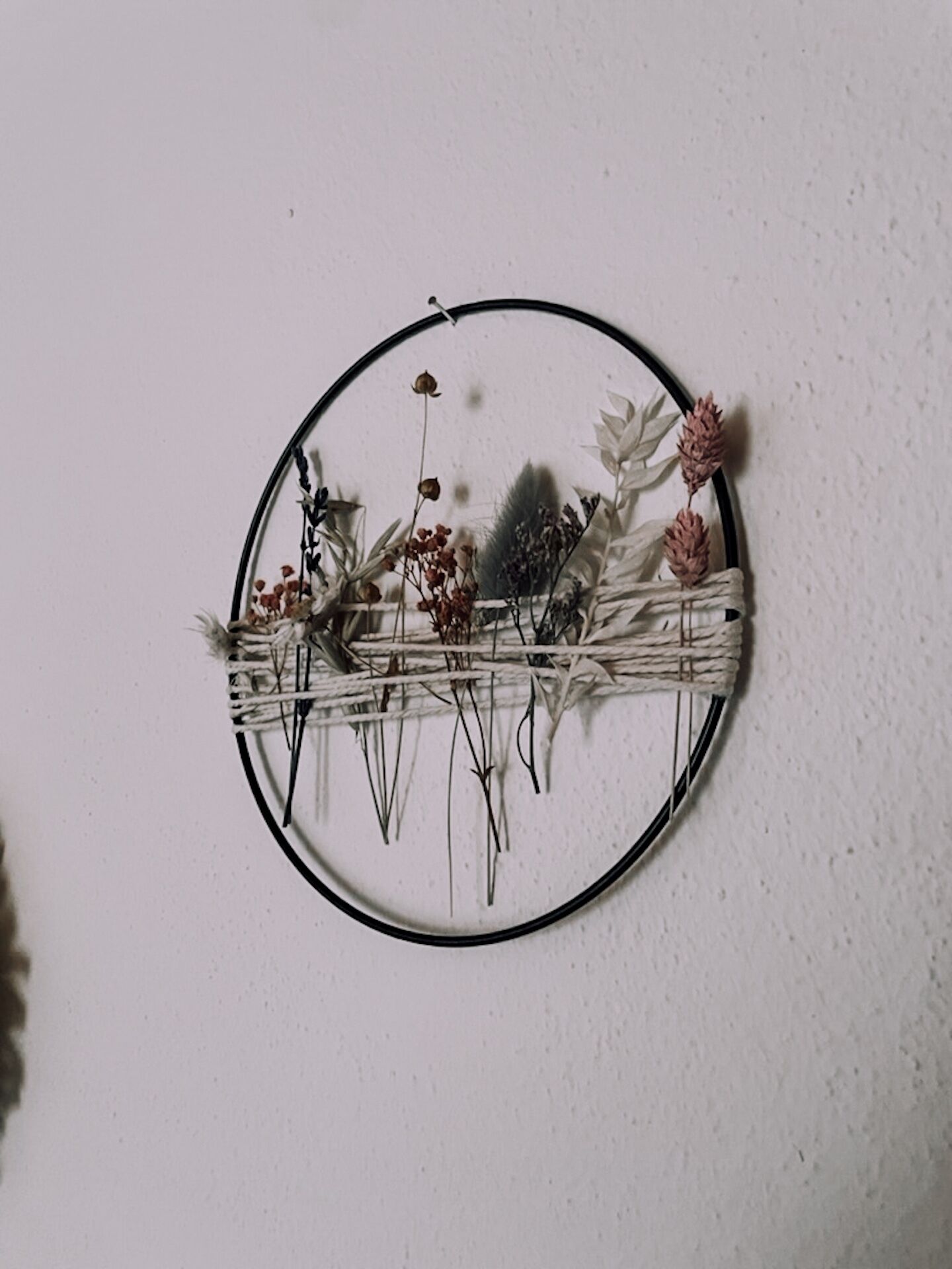A circular wall decoration with dried plants and flowers.
