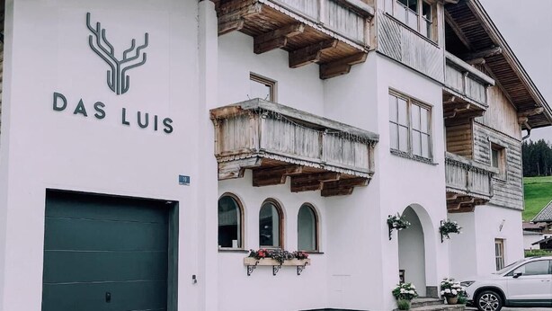 Ein Gebäude mit einem Schild, auf dem 'DAS LUIS' steht, und einer grünen Tür.