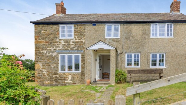 A stone cottage with a wooden front door, a small porch, and a sign reading 'JESSOP'S COTTAGE.' - 3 Bed in Dorchester (oc-50290) (Hilfield)