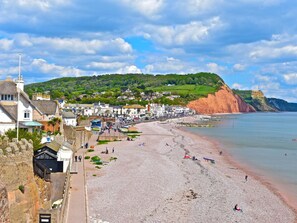 A coastal town with a pebble beach, historic buildings, and a cliffside.