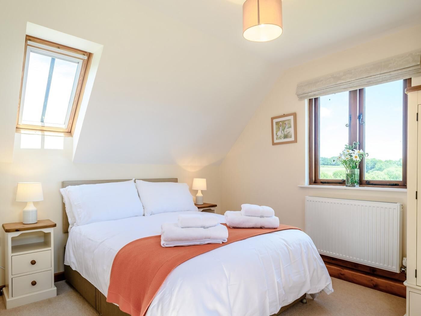 Un dormitorio con una cama, dos mesitas de noche, una ventana y un radiador.