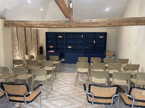 Habitación con techo alto, vigas de madera a la vista, pared con diseño y un estante azul con diversos objetos.
