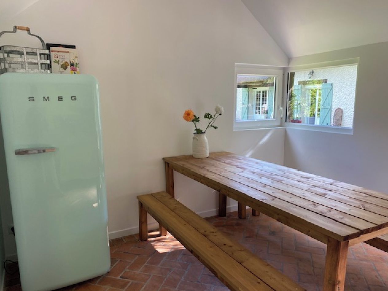 Une cuisine avec un réfrigérateur Smeg vintage, une table en bois et un banc.