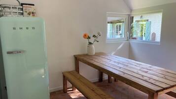 Une cuisine avec un réfrigérateur Smeg vintage, une table en bois et un banc.