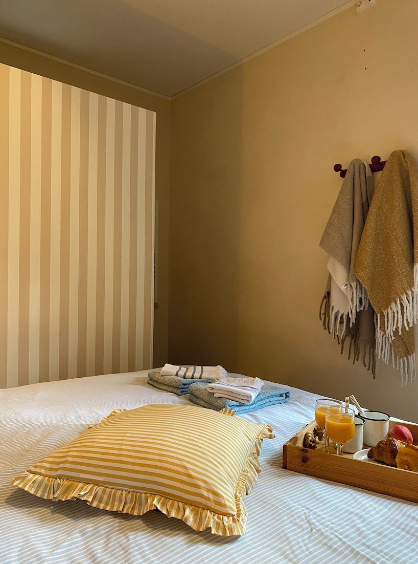 Une chambre d’hôtel avec un lit, des rideaux à rayures, un porte-serviettes et un plateau de petit-déjeuner.