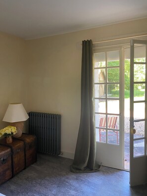 A room with a radiator, a lamp, a wooden chest, and a door leading outside.