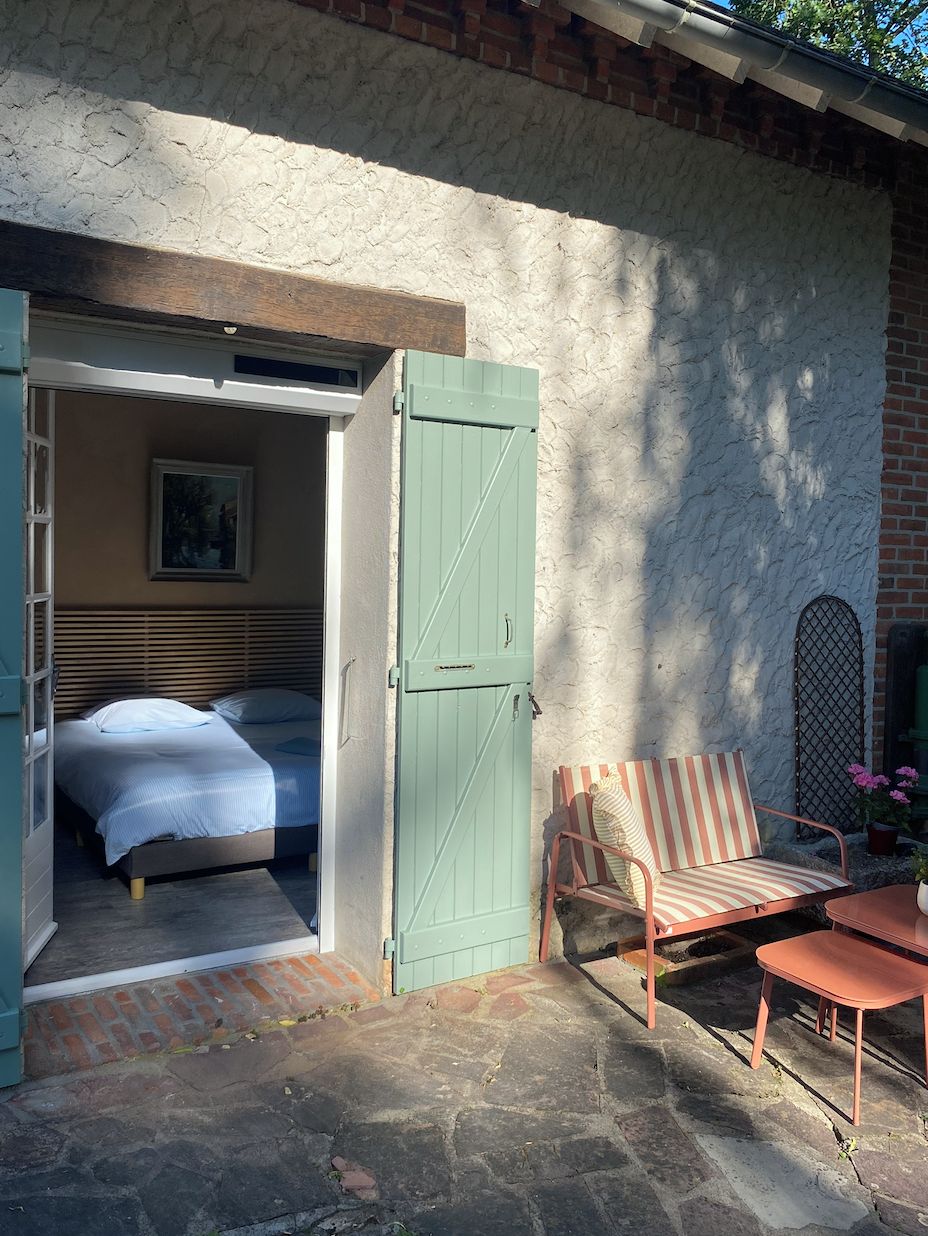 Una puerta abierta que da a un dormitorio con una cama y una silla afuera.