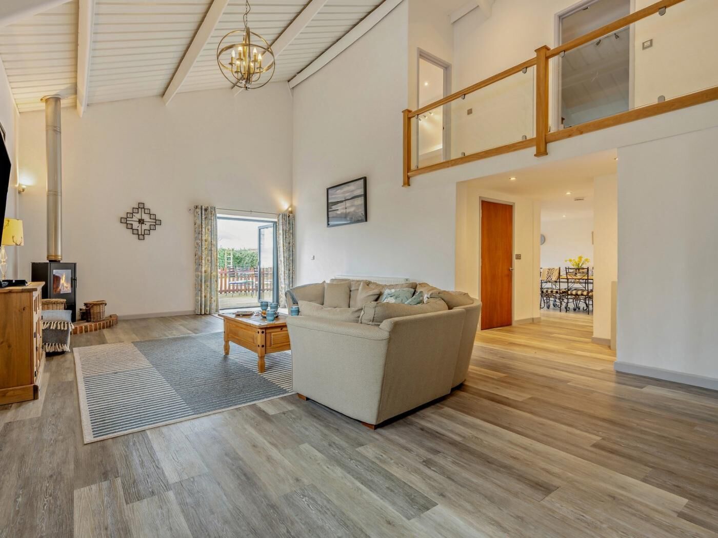 A spacious living area with a sofa, a wooden coffee table, a fireplace, and a staircase leading to an upper level.