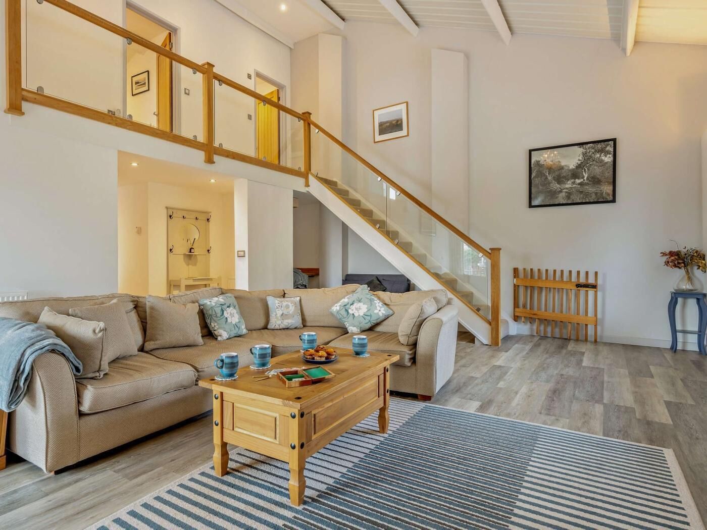 A spacious living area with a wooden staircase, a sofa set, a coffee table, and a framed picture on the wall.