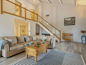A spacious living area with a wooden staircase, a sofa set, a coffee table, and a framed picture on the wall. - 3 Bed in Blandford Forum (oc-49993) (Milton Abbas)