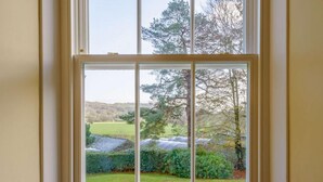 A window with a view of a green landscape, including trees and a grassy field. - 4 Bed in Hawkshead (oc-llh03) (Hawkshead)