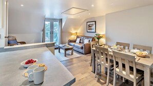A modern kitchen with a dining area, a sofa, and a large window. - 2 Bed in Saundersfoot (oc-50550) (Saundersfoot)