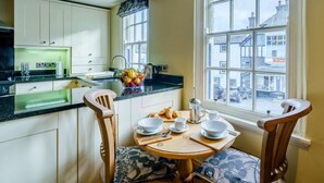Une cuisine avec un coin repas, une fenêtre donnant sur des immeubles et une table mise pour le petit-déjeuner.