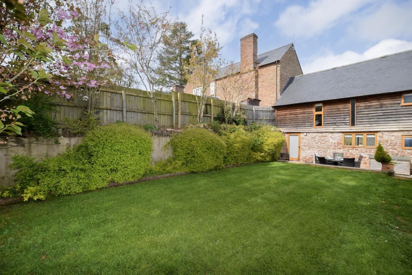 A house with a stone facade, a wooden deck, and a well-maintained lawn.