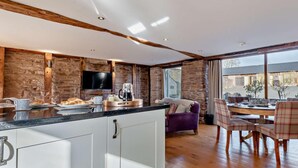 Una cocina moderna con pared de piedra, vigas de madera y un ventanal grande.