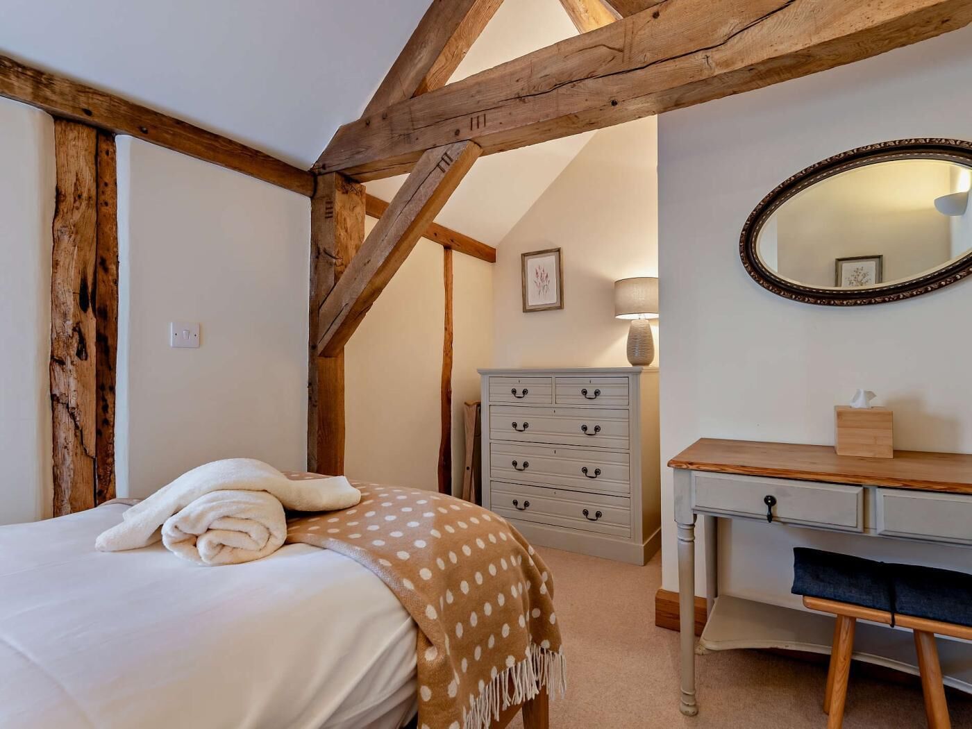 A bedroom with a bed, a dresser, a mirror, and a lamp.