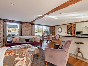 A spacious living area with a sofa, armchairs, and a dining table. A kitchen with modern appliances is visible in the background. - 3 Bed in Bromyard (oc-50507) (Pencombe)