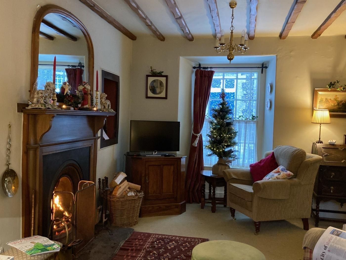 Un salon chaleureux avec une cheminée, un téléviseur, un sapin de Noël et un coin salon confortable.