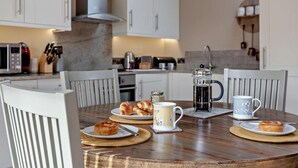 Una cucina moderna con mobili bianchi, una macchina da caffè e un tavolo da pranzo apparecchiato per la colazione.