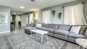 Una sala de estar moderna con un sofá gris, una mesa de centro blanca y alfombras estampadas.
