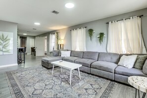 A modern living room with a grey sofa, a white coffee table, and patterned rugs. - 6 Mi to Dtwn! Family Home w/ Hot Tub in Houston (Houston)