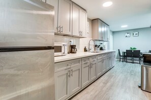 A modern kitchen with stainless steel appliances, light wood flooring, and a dining area with a table and chairs. - 6 Mi to Dtwn! Family Home w/ Hot Tub in Houston (Houston)