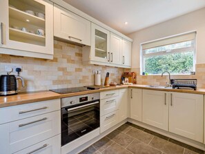 A modern kitchen with white cabinets, a Bosch oven, a coffee maker, and a window providing natural light. - 5 Bed in Hawkshead (oc-llh55) (Outgate)