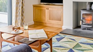 Ein gemütliches Wohnzimmer mit einem Holztisch, einer Landkarte, einem Glas Wasser und einem Kamin.