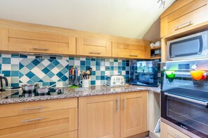 Eine moderne Küche mit Holzausstattung, einer Granit Arbeitsplatte, einem Bosch Backofen und einer Mikrowelle.