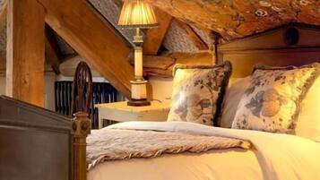 A bedroom with a wooden bed frame, a white bedspread, and a patterned ceiling.