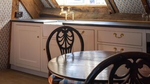Et køkken med et vindue, en vask, en stol og et bord.