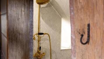 A wooden door with a brass shower head and a towel rack.