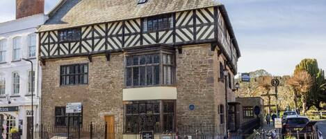 A traditional building with a stone facade and timber framing, a signboard, and a bicycle parked outside.