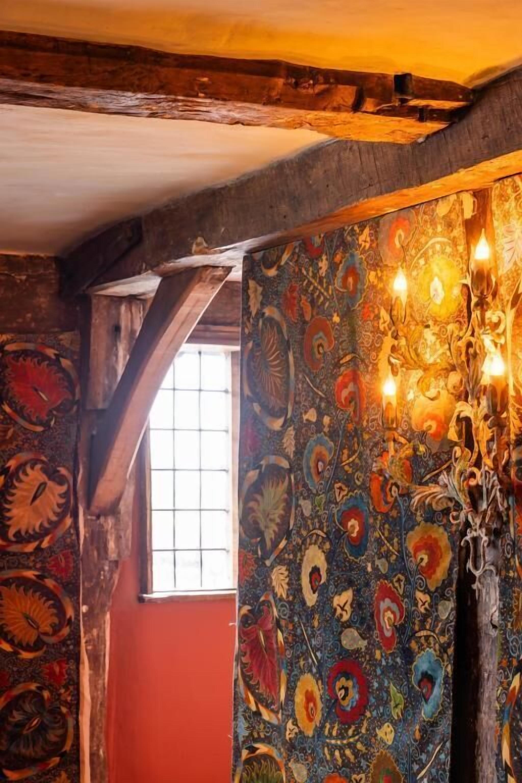 A room with a patterned wall, a window, and a chandelier.