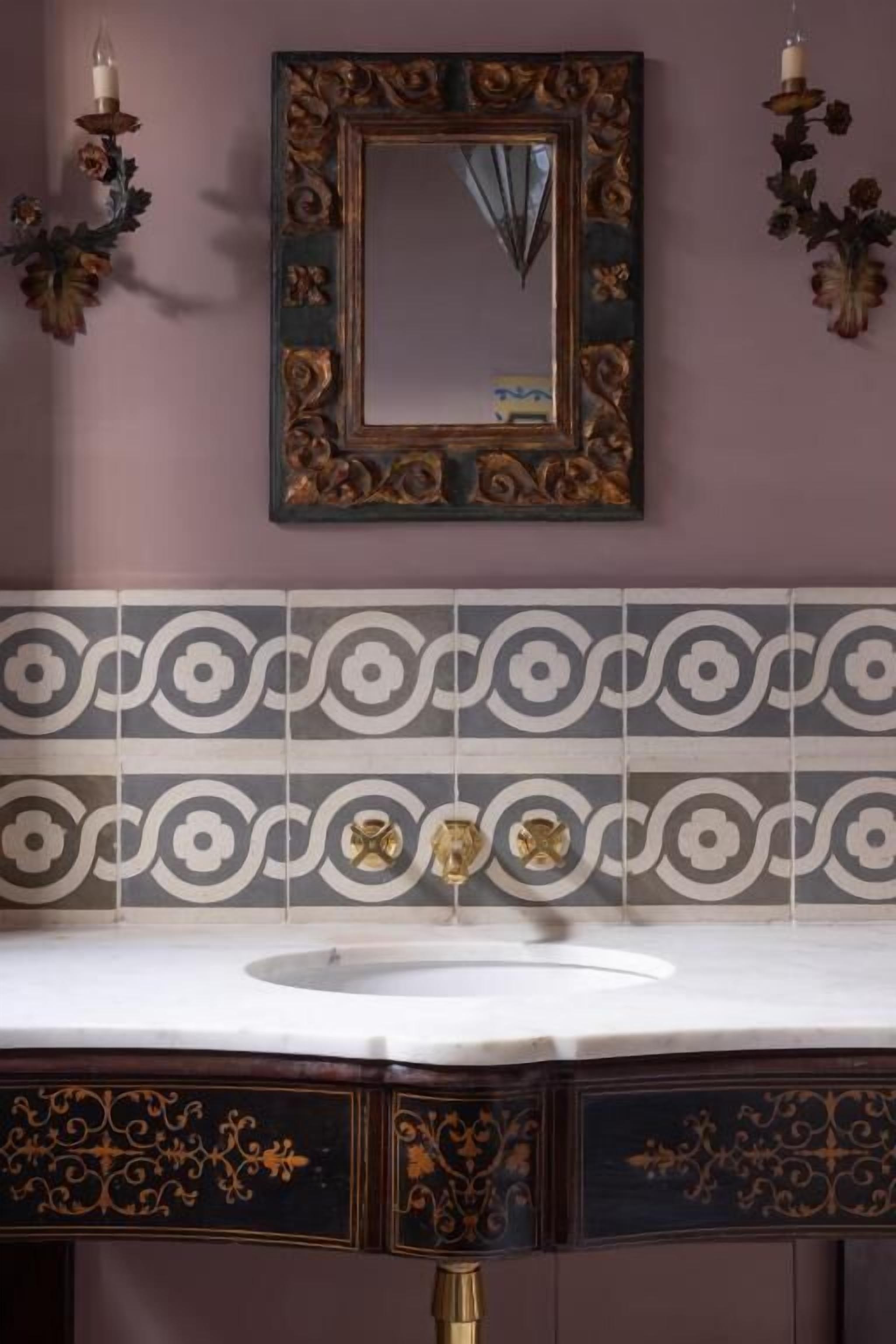 A bathroom with a vanity, mirror, and decorative wall sconces.