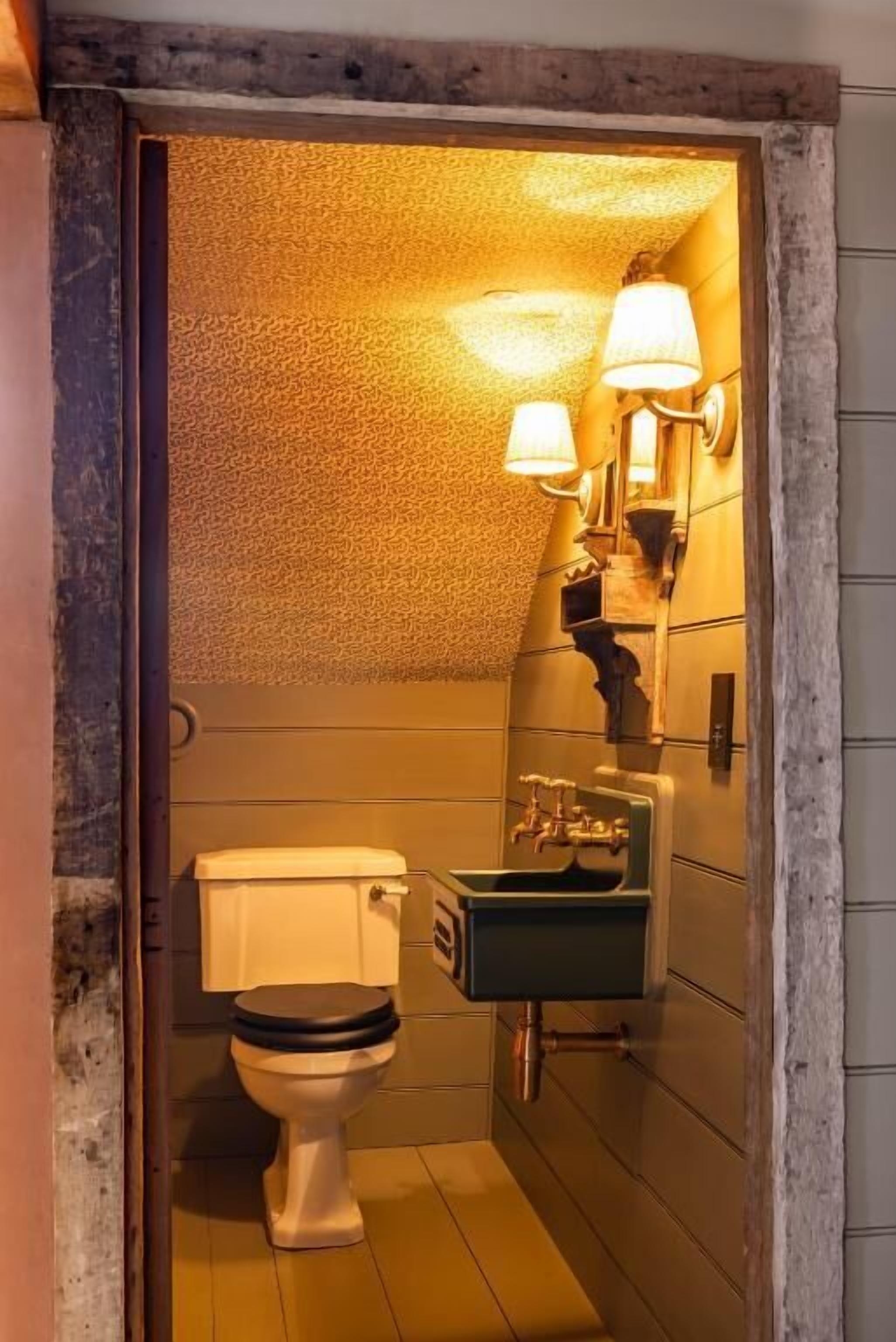 Une salle de bain équipée de toilettes, d’un lavabo et d’appliques murales.