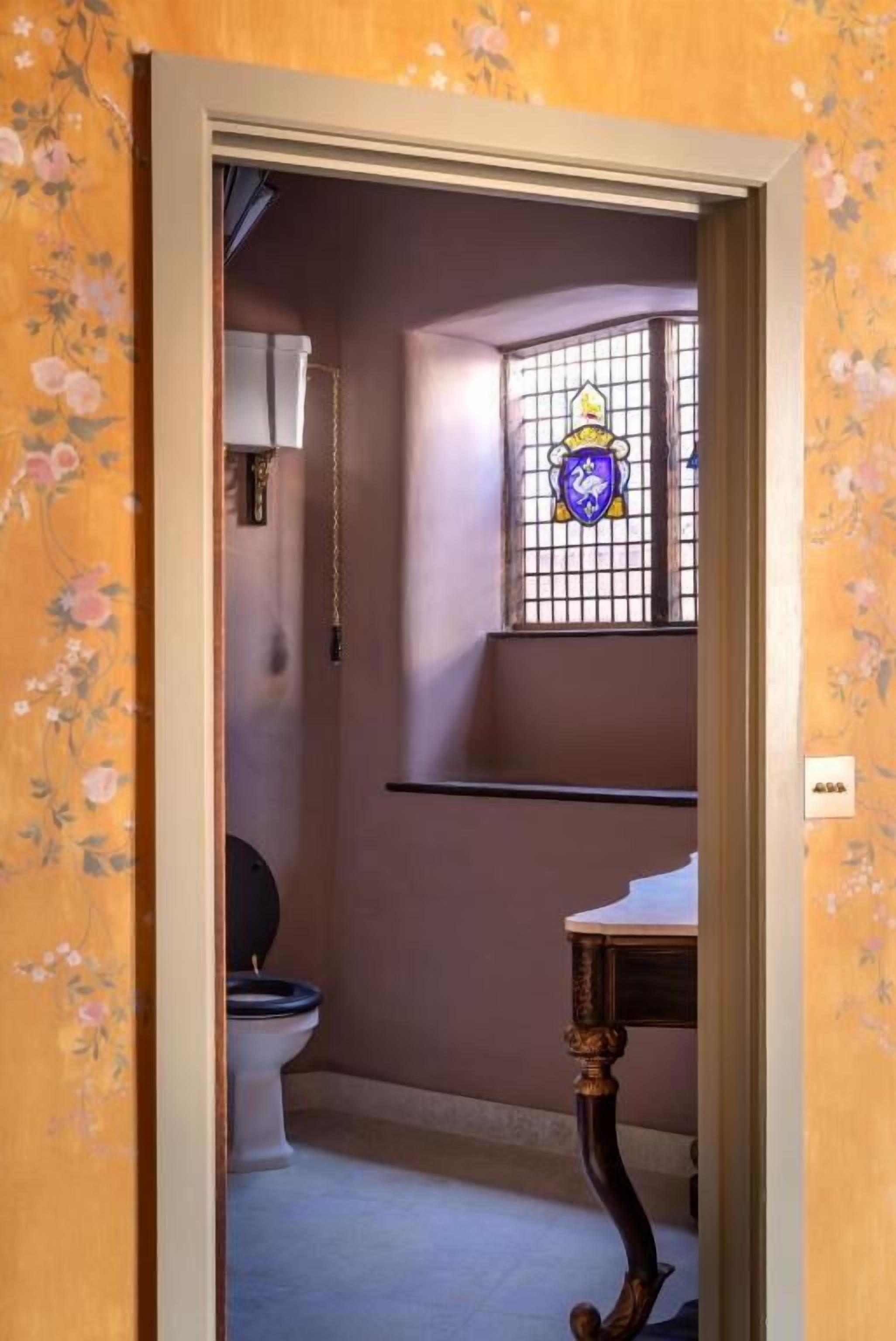 A bathroom with a toilet, a sink, and a window with a decorative glass design.