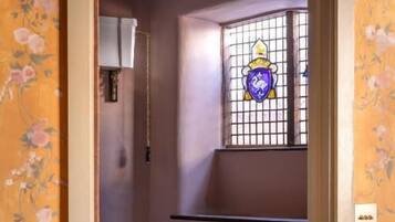 A bathroom with a toilet, a sink, and a window with a decorative glass design.