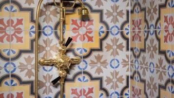 Un baño con un cabezal de ducha decorativo y un pared con azulejos estampados.