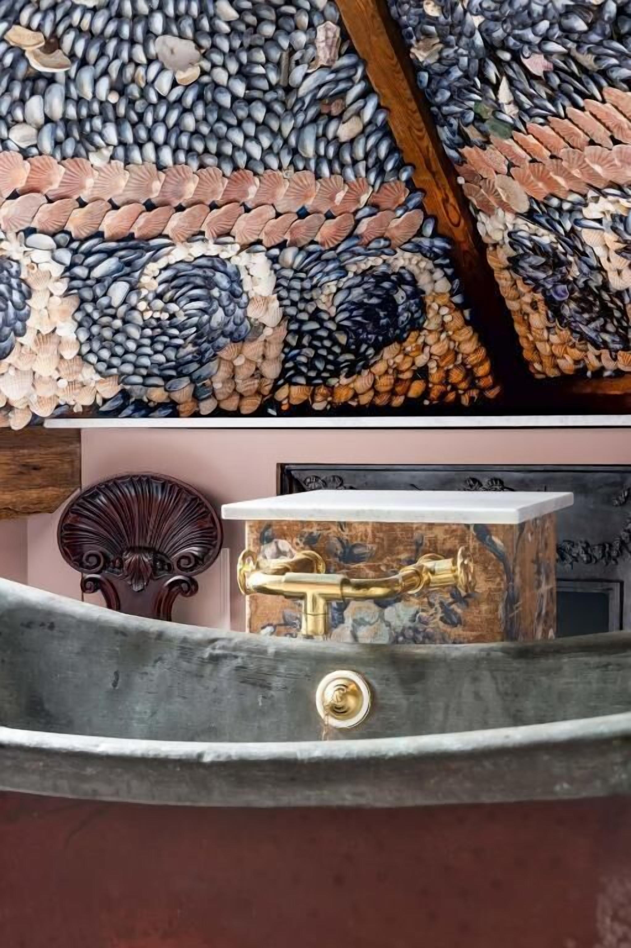 Une baignoire au design rétro, un mur décoratif orné d’un motif en mosaïque et une chaise en bois.