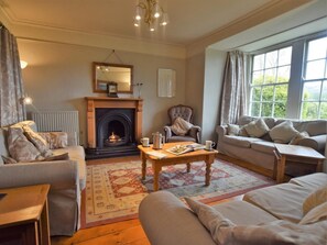 A cozy living room with a fireplace, a sofa, a chair, and a coffee table. - 7 Bed in Hawkshead (oc-llh47) (Hawkshead)