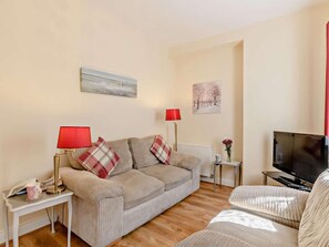 A living room with a sofa, two side tables, a red lamp, a television, and two wall-mounted paintings. - 1 Bed in Cromer (oc-50438) (Cromer)
