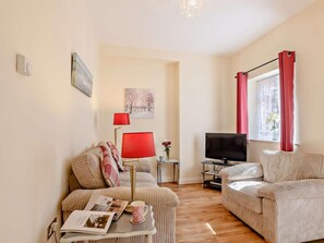 A living room with a sofa, a television, a small table with a magazine and a mug, and a window with curtains. - 1 Bed in Cromer (oc-50438) (Cromer)