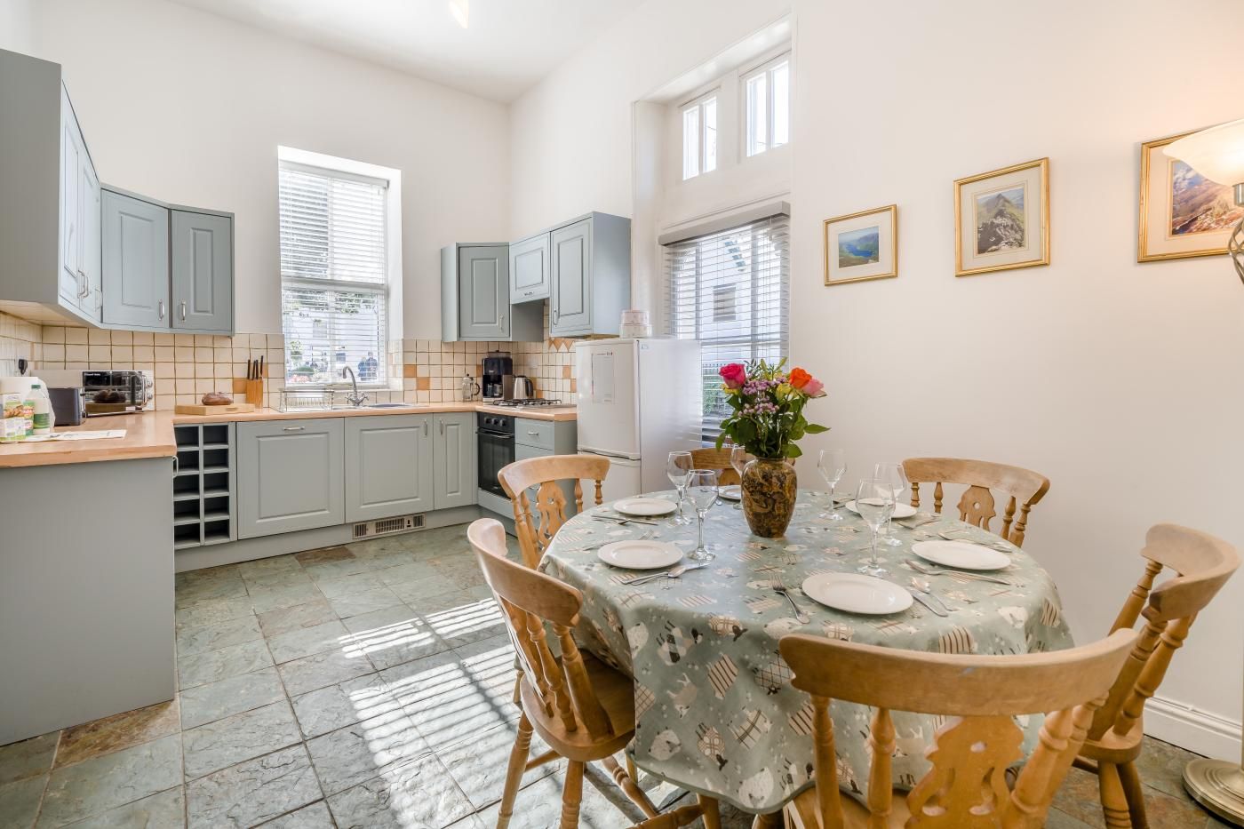 Un coin repas avec une table ronde dressée pour quatre personnes, entourée de chaises en bois.