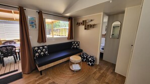 Ein kompakter Wohnbereich mit Sofa, einem kleinen runden Tisch, einem Spiegel und Blick ins Freie.