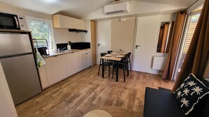 Eine kompakte Küche mit Mikrowelle, Kühlschrank und einem Essbereich mit Tisch und Stühlen.