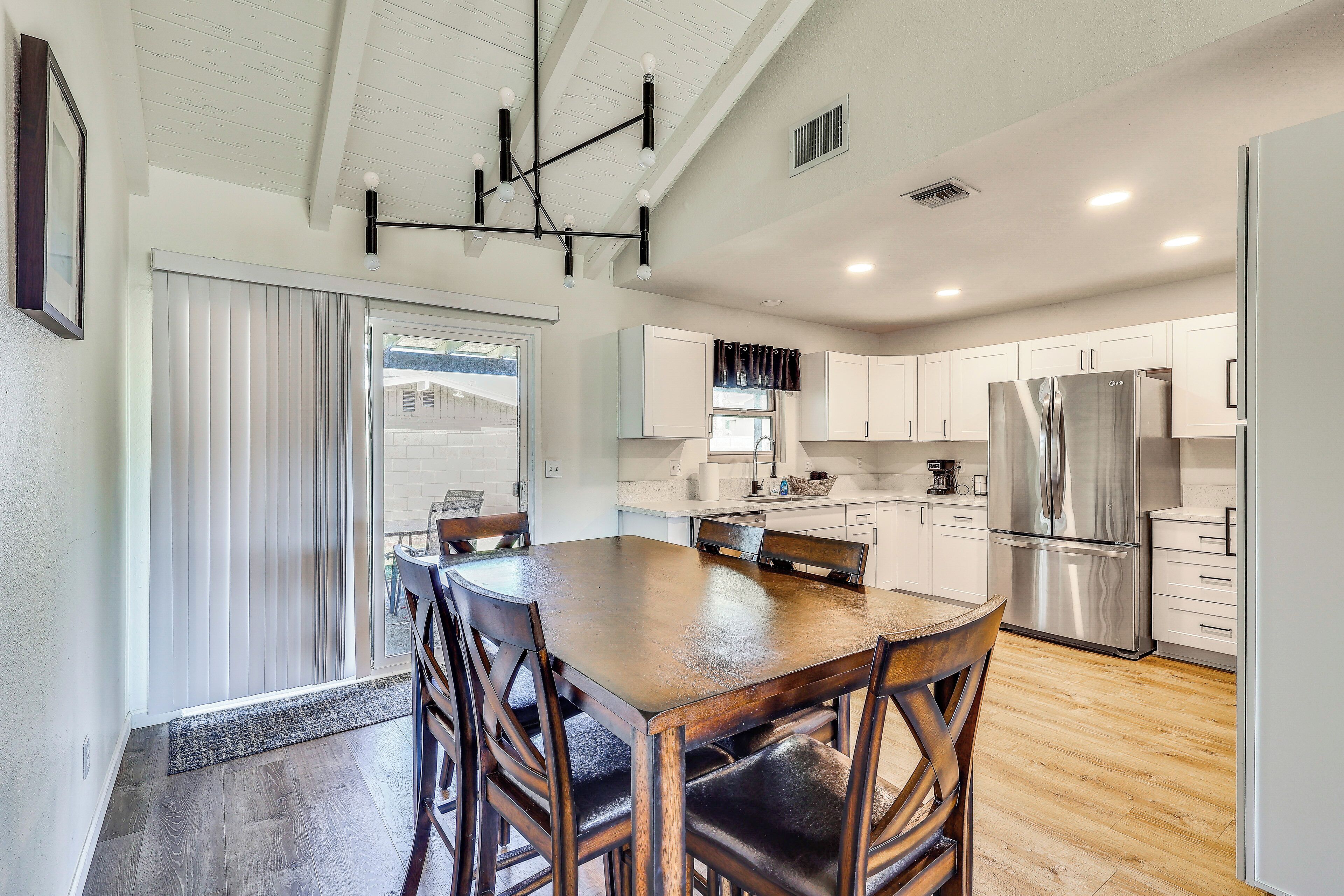 A modern kitchen with a large island, stainless steel appliances, and a dining area with wooden chairs.
